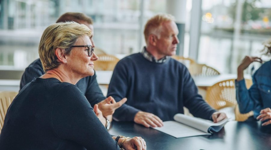 Senior,Businesswoman,Sitting,In,Boardroom,Meeting.,Group,Of,Business,People